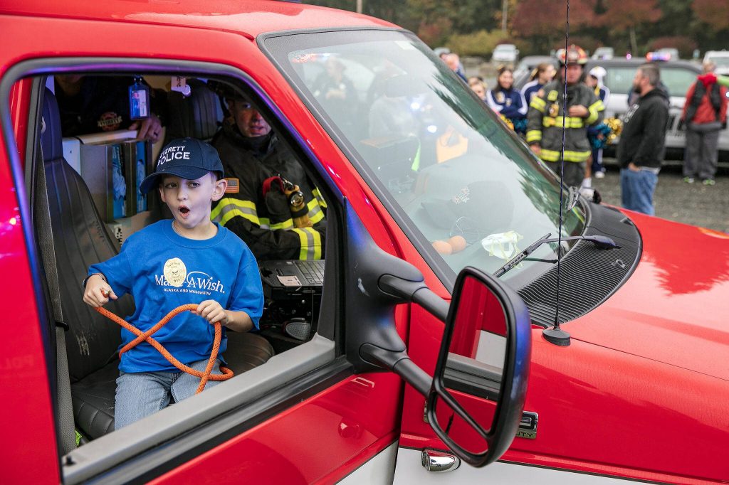 Ryan Berry / The Herald
Carson, 7, reacts as he gets an opportunity to use some of the gear inside an Everett ambulance during a surprise Make-A-Wish sendoff Oct. 21 at Thornton A. Sullivan Park in Everett. Dozens rallied together to lift up Carson before he and his family headed off to Disneyland.
