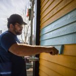 Evan Reed helps repaint the yellow exterior of the Catalyst Cafe along Hewitt Avenue on Thursday, Dec. 21, 2023 in Everett, Washington. (Olivia Vanni / The Herald)