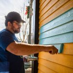 Evan Reed helps repaint the yellow exterior of the Catalyst Cafe along Hewitt Avenue on Thursday, Dec. 21, 2023 in Everett, Washington. (Olivia Vanni / The Herald)