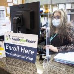 Annaberies Colmena, a patient navigator, sits behind an open enrollment flyer at Sea Mar on Friday, Dec. 9, 2022 in Everett, Washington. (Olivia Vanni / The Herald)