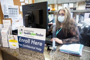 Annaberies Colmena, a patient navigator, sits behind an open enrollment flyer at Sea Mar on Friday, Dec. 9, 2022 in Everett, Washington. (Olivia Vanni / The Herald)