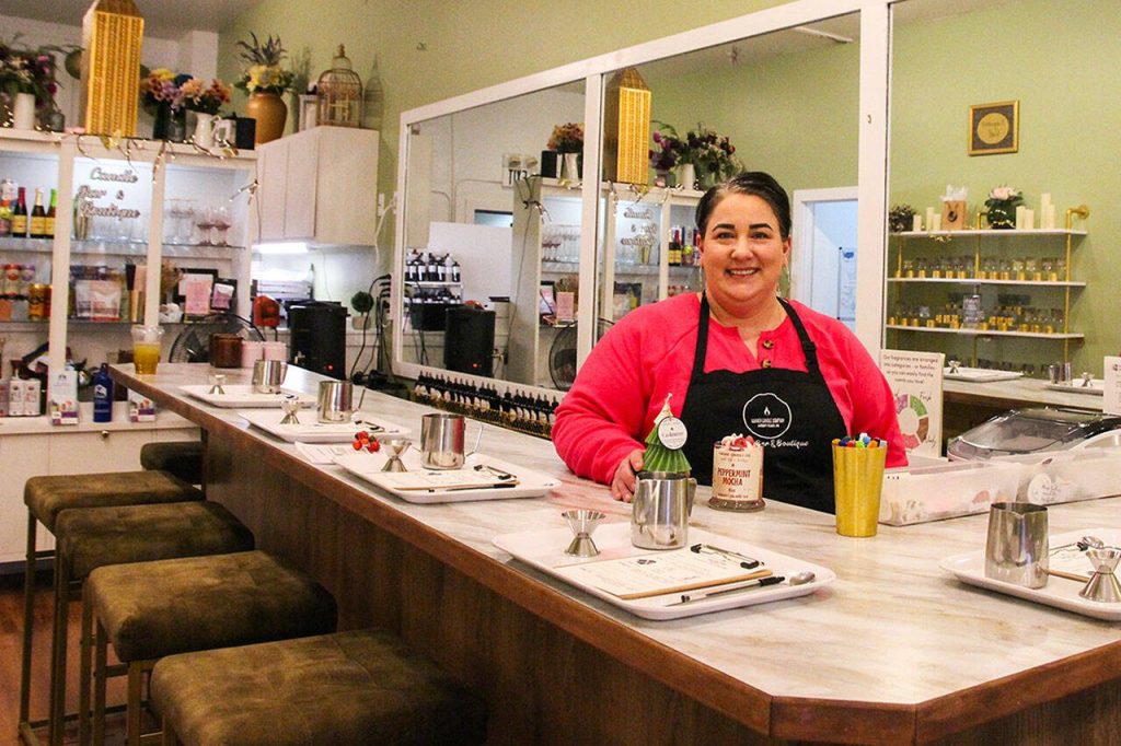Megan Varner-Duckett, owner of Varner Candle Company, stands behind the bar where guests can enjoy a drink and craft their own candles. (Photo by Luisa Loi)