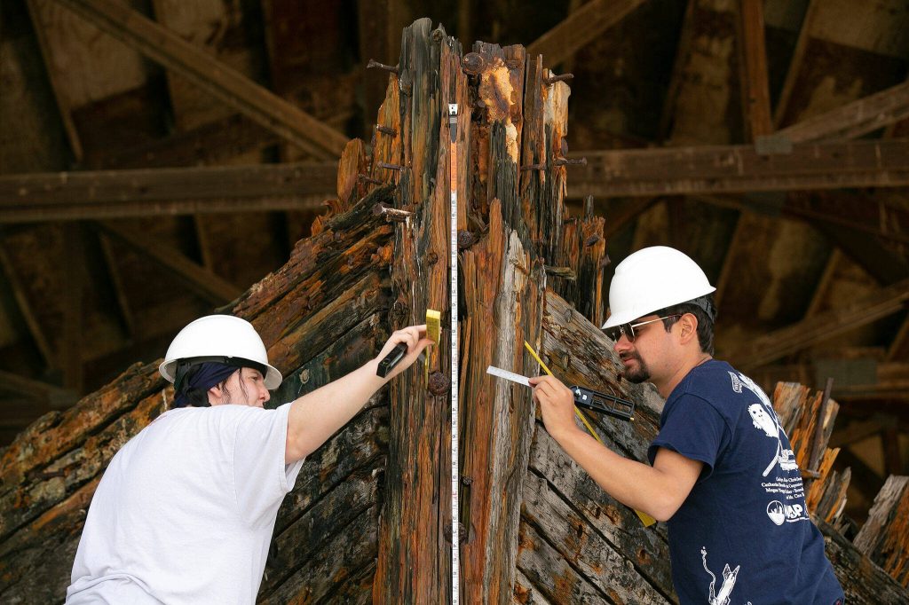 Texas A&M masters students Meagan Clyburn, left, and Sam Werthan take measurements of the roughly 13-foot high stem of the Equator on Wednesday, June 7, 2023, during a two-week survey of the vessel at its resting place in Everett, Washington. (Ryan Berry / The Herald)