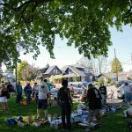 People gather in the shade during a community gathering to distribute food and resources in protest of Everetts expanded no sit, no lie ordinance Sunday, May 14, 2023, at Clark Park in Everett, Washington. (Ryan Berry / The Herald)