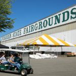 People zip around the fairgrounds on a golf cart as preparations for the state fair are underway on Monday, Aug. 22, 2022, at the Evergreen State Fairgrounds in Monroe, Washington. (Ryan Berry / The Herald)