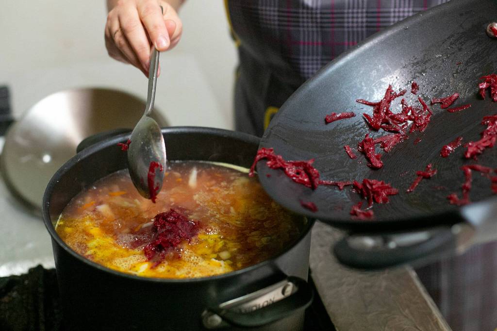 Cook Ivanna Tomashevska adds shredded beets to finish off a batch of borscht at European Deli Svitlana. (Ryan Berry / The Herald)