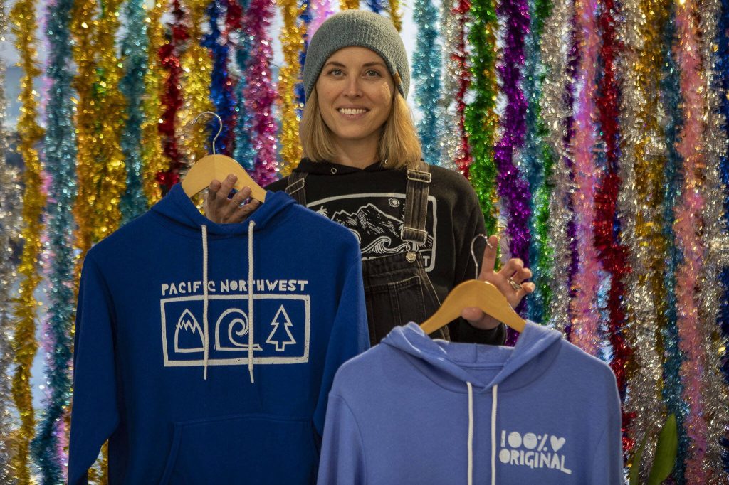 Phoebe Carpenter Eells poses for a photo with some of her designs at elSage in Mount Vernon, Washington, on Thursday, Dec. 14, 2023. (Annie Barker / The Herald)