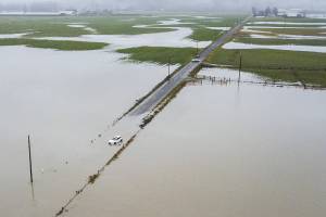 A car sits abandoned surrounded by floodwater along 28th Avenue NW on Wednesday, Dec. 6, 2023 in Stanwood, Washington. (Olivia Vanni / The Herald)