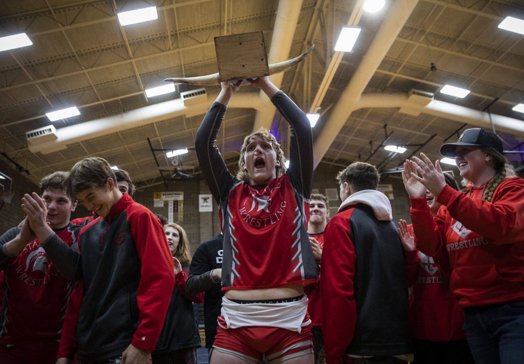 Stanwoods Elijah Fleck lifts the Battle of the Bull trophy in celebration of beating Arlington on Jan. 24, 2023 in Arlington. (Olivia Vanni / The Herald)