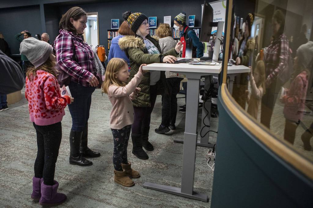 Leane Thompson, right, and her daughter Ivory Thompson, to her left, use a computer during the grand reopening of the Edmonds Library in Edmonds, Washington on Saturday, Jan. 13, 2024. (Annie Barker / The Herald)