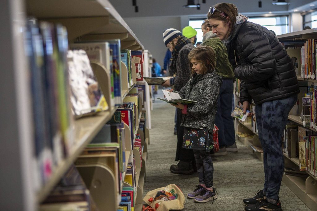 Matilda Morton, 9, left, and Molly Norton, browse shelves and celebrate during the grand reopening of the Edmonds Library in Edmonds, Washington on Saturday, Jan. 13, 2024. (Annie Barker / The Herald)