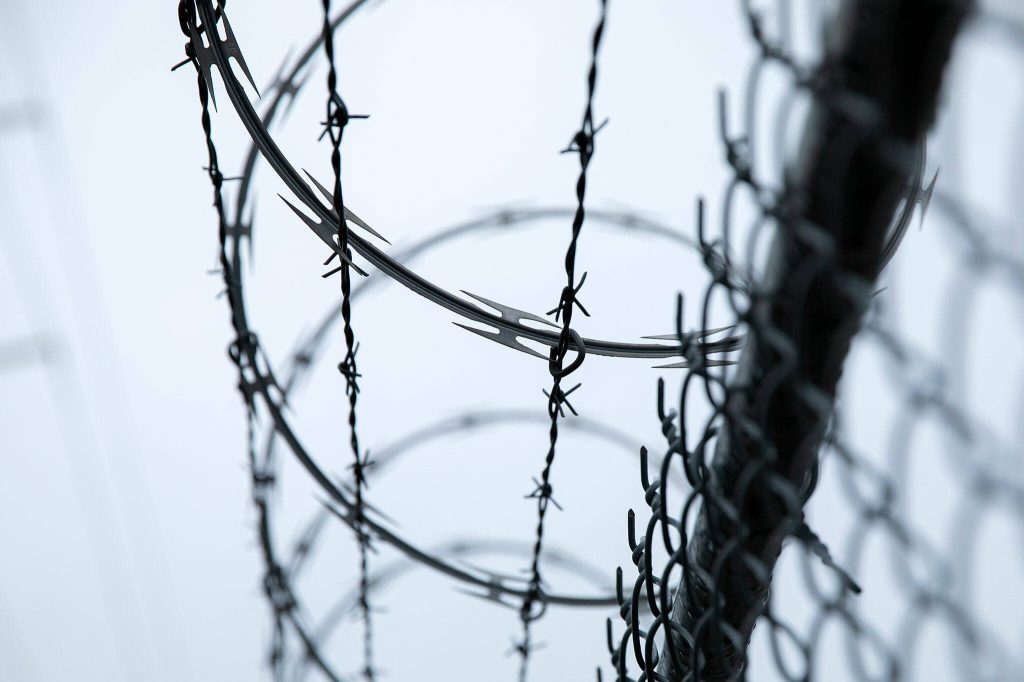 Razor wire lines the entirety of Pigeon Creek Trail on Tuesday, Jan. 2, 2024, in Everett, Washington. The high, protected fence keeps people from getting into a Port of Everett shipping yard. (Ryan Berry / The Herald)