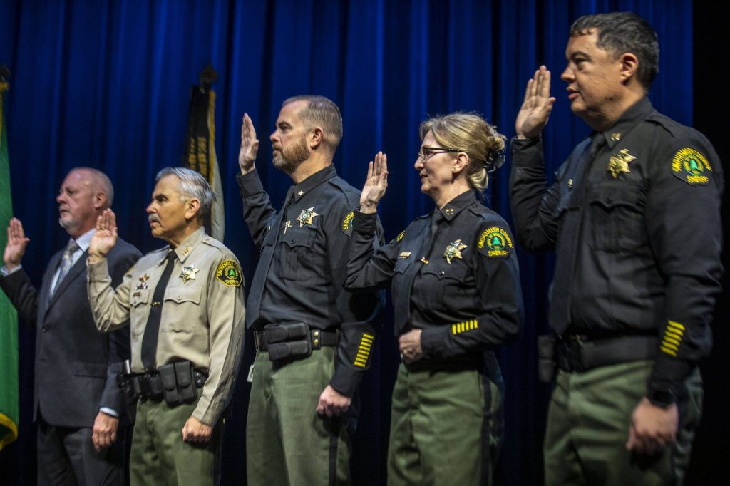 Left to right, SRDTF Commander Jay Baines, Chief Pilot Bill Quistorf, Corrections Major David Hall, Corrections Special Operations Captain Roxanne Marler, and Corrections Detention Captain Robert Ogawa, take an oath of office at the PUD auditorium in Everett, Washington on Tuesday, Jan. 2, 2024. (Annie Barker / The Herald)