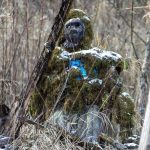 A figure known as the Lake Stevens Bigfoot-Moss Man-Sasquatch sits among trees and along the Stevens Creek stream on Lundeen Parkway in Lake Stevens. (Annie Barker / The Herald)