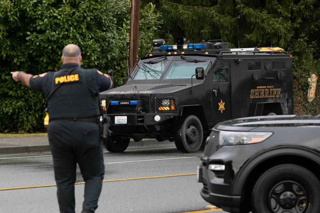 An Everett Police officer directs an armored vehicle from the Snohomish County Sheriffs Department during a standoff related to a shooting at The Bluffs Apartments on West Casino Road on Monday, Jan. 22, 2024, in Everett, Washington. (Ryan Berry / The Herald)