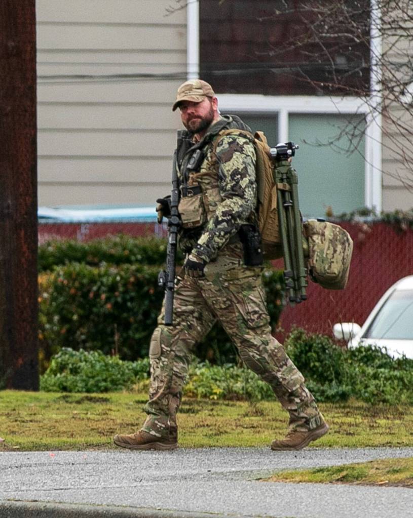 A sharpshooter walks over to The Bluffs Apartments during a standoff following a shooting Monday, Jan. 22, 2024, in Everett, Washington. (Ryan Berry / The Herald)