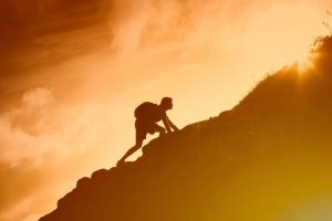 Silhouette of man climbing up a mountain