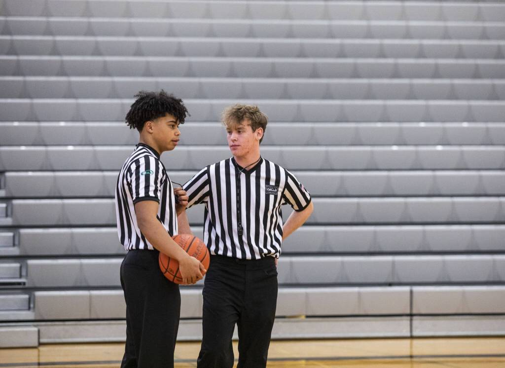 Chandler Hyde, left, and Matthew Meadows, right, talk during halftime at a basketball game Jan. 16 at Lynnwood High School in Bothell. (Olivia Vanni / The Herald)