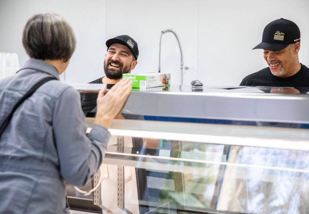 Earth and Ocean co-owners Chris Mills, left, and Fermin Lopez chat with a customer. (Olivia Vanni / The Herald)