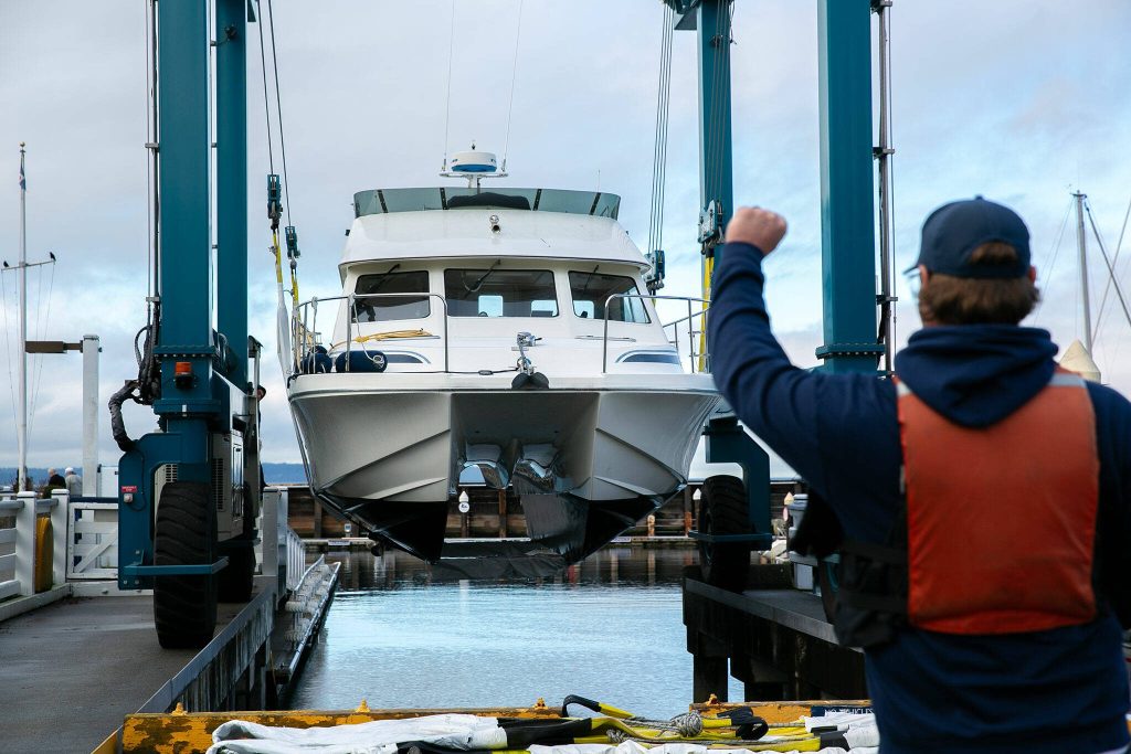 A boat comes up on the travel lift at the Port of Edmonds before being moved to a maintenance yard on Wednesday, Jan. 24, 2024, in Edmonds, Washington. (Ryan Berry / The Herald)