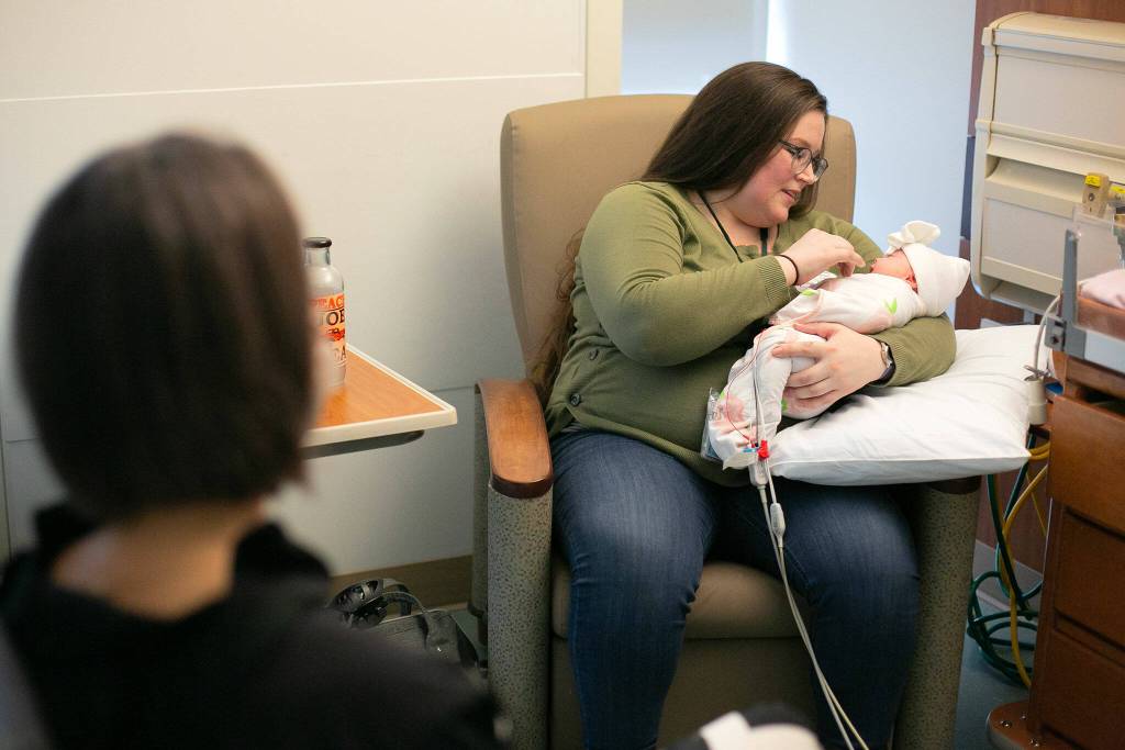 Aunalisa Evans holds her daughter Julia while speaking with her PCAP case manager Jennifer Ross at the Providence NICU on Thursday, Jan. 25, 2024, in Everett, Washington. (Ryan Berry / The Herald)