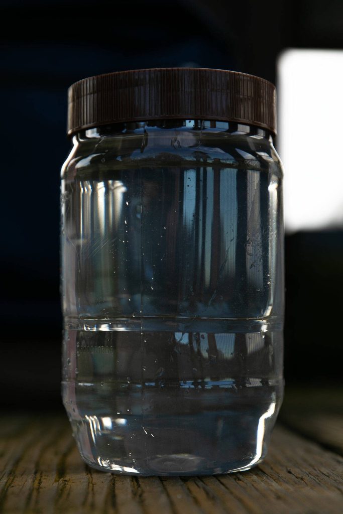 A peanut butter jar is used to hold a sample of stormwater collected from a drain below the Port of Everett boardwalk Friday, Feb. 16, 2024, in Everett, Washington. (Ryan Berry / The Herald)