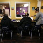 Cocoon House advocate Morgan Huber (right) talks with teens gathered at the nonprofits U-Turn drop-in center on Broadway in Everett Dec. 13 2016. (Ian Terry / The Herald)