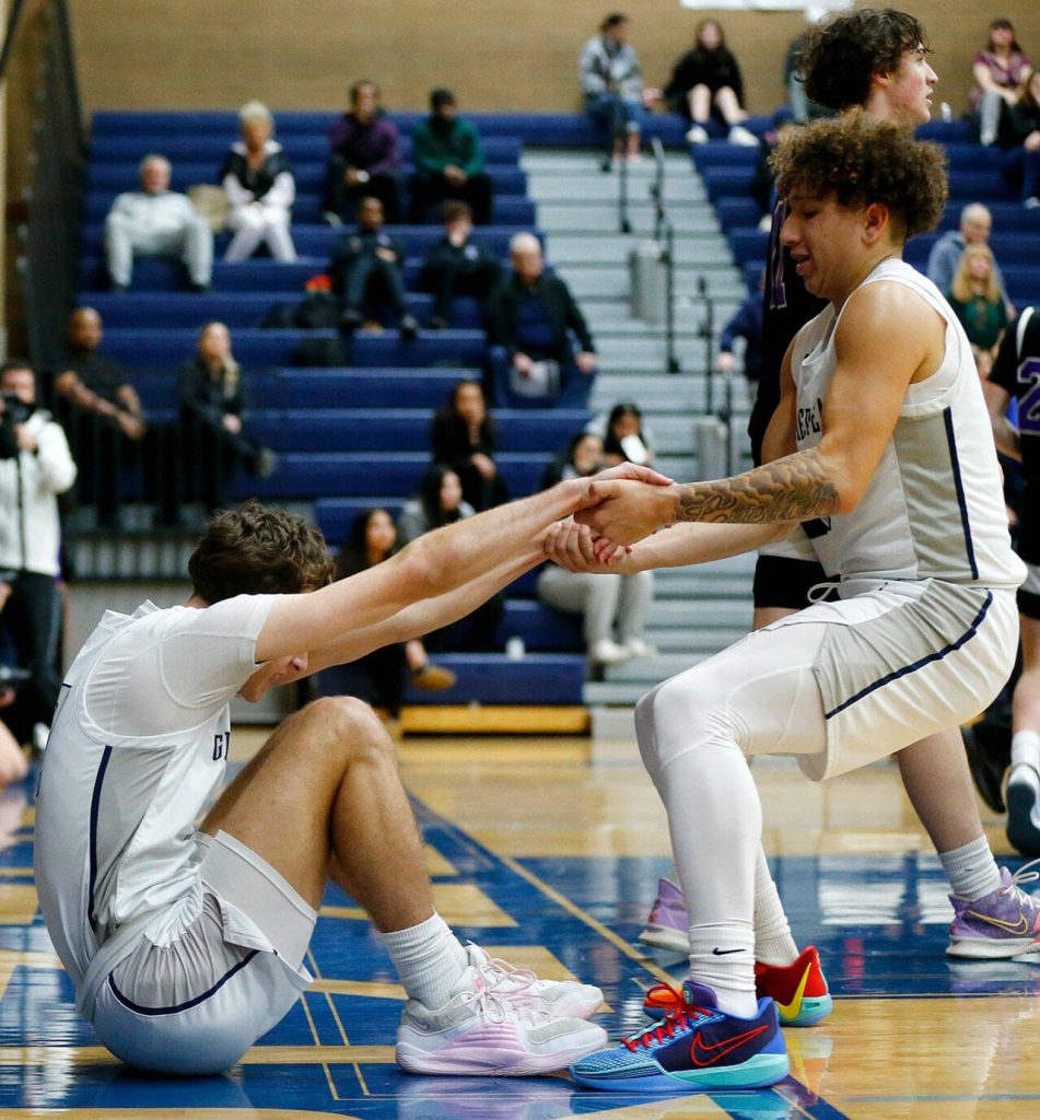 Glacier Peaks Isaiah Cuellar helps up teammate Josiah Lee during a 4A boys basketball game against Kamiak on Thursday, Feb. 1, 2024, at Glacier Peak High School in Snohomish, Washington. (Ryan Berry / The Herald)
