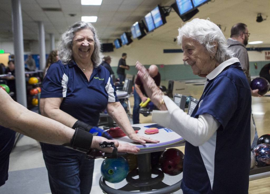 Carol Perry high fives her teammates after getting a strike during league bowling at Strawberry Lanes on Wednesday, Feb. 26, 2020 in Marysville , Wa. (Olivia Vanni / The Herald)