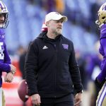 Washington offensive coordinator Ryan Grubb, center, talks with quarterback Dylan Morris (5) and quarterback Michael Penix Jr. (9) as they warm up before an NCAA college football game against Washington State, Saturday, Nov. 25, 2023, in Seattle. (AP Photo/Lindsey Wasson)