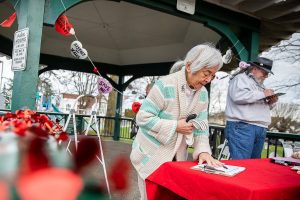 Lyla Anderson and others sign a petition to save the Clark Park gazebo during a “heart bomb” event hosted by Historic Everett on Saturday, Feb. 17, 2024 in Everett, Washington. (Olivia Vanni / The Herald)