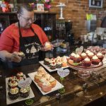 Mom and Pops Cakery owner Colleen Dunn picks out a Valentines Day-themed cupcake for a customer on Wednesday, Feb. 14, 2024 in Everett, Washington. (Olivia Vanni / The Herald)