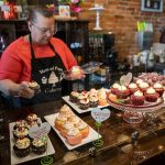 Mom and Pops Cakery owner Colleen Dunn picks out a Valentine’s Day themed cupcake for a customer on Wednesday, Feb. 14, 2024 in Everett, Washington. (Olivia Vanni / The Herald)