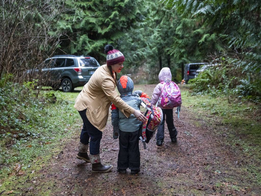 Co-founder of Springwood Forest School Heather White helps a student put on their backpack on Monday, Jan. 22, 2024 in Camano Island, Washington. (Olivia Vanni / The Herald)