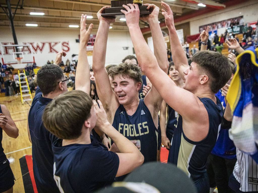 Arlingtons Leyton Martin holds up the 3A boys district championship trophy in celebration on Saturday, Feb. 17, 2024 in Marysville, Washington. (Olivia Vanni / The Herald)