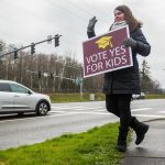 Jaime Benedict, who works as a substitute teacher, waves to drivers on the corner of Mukilteo Speedway and Harbor Pointe Boulevard while holding a sign in support of the $240 million capital bond proposal for Mukilteo School District on Tuesday, Feb. 11, 2020 in Mukilteo, Wash. (Olivia Vanni / The Herald)