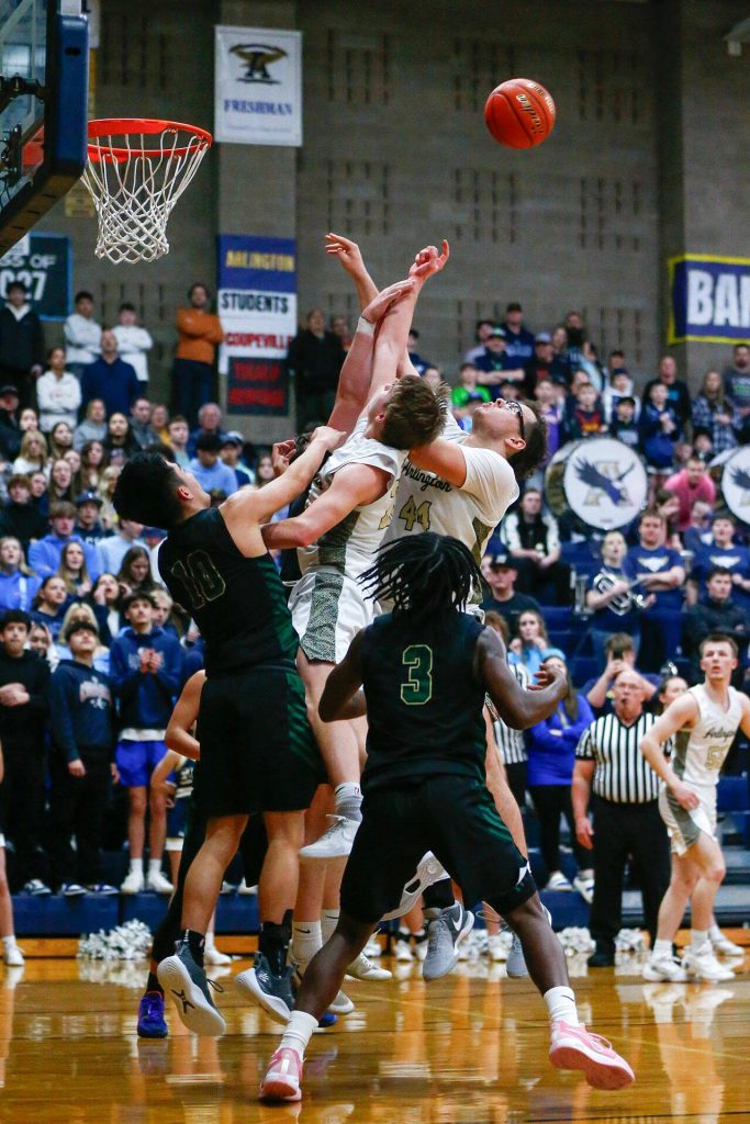 Arlington and Marysville Getchell players all leap for a rebound during a playoff matchup at Arlington High School on Saturday, Feb. 24, 2024, in Arlington, Washington. (Ryan Berry / The Herald)