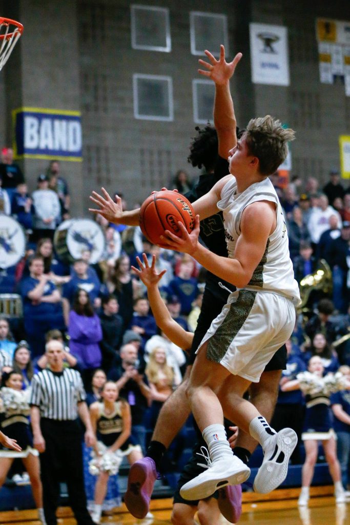 Arlingtons Leyton Martin weaves midair to score against Marysville Getchell during a playoff matchup at Arlington High School on Saturday, Feb. 24, 2024, in Arlington, Washington. (Ryan Berry / The Herald)