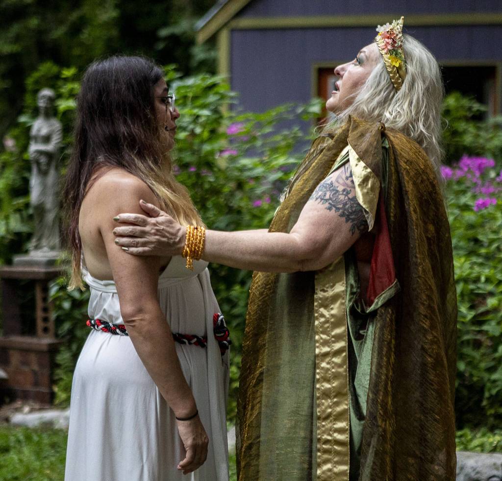 Aedis LaVeau, left, listens to a message from Demeter, the Greek goddess of agriculture, through Archpriestess Belladonna Laveau during the Lammas and Wicker Man ritual at the Aquarian Tabernacle Church in Index, Washington, in August 2023. (Annie Barker / The Herald)