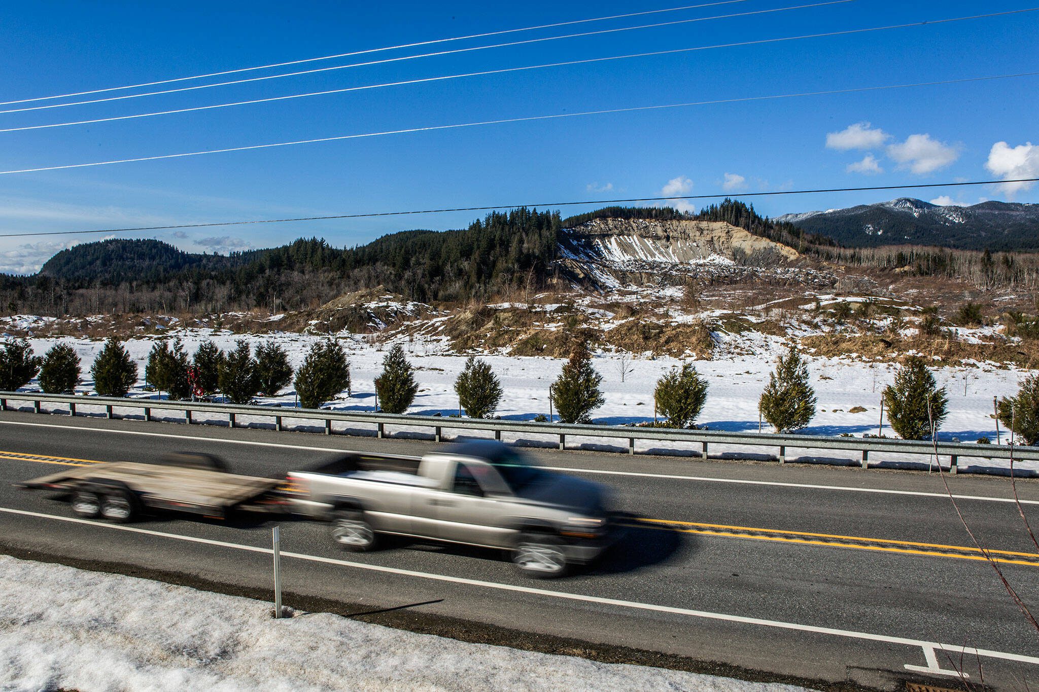 A car pulling an empty trailer drives eastbound along Highway 530 in front of the Oso mudslide site on Thursday, Feb. 21, 2019 in Oso, Wash. (Olivia Vanni / The Herald)