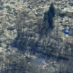 The blue-tarped roof of a house destroyed by the massive mudslide that killed at least eight people Saturday and left dozens missing is visible at right in this aerial photo, Monday, March 24, 2014, near Arlington, Wash. The search for survivors grew Monday, raising fears that the death toll could climb far beyond the eight confirmed fatalities. (AP Photo / Ted S. Warren)