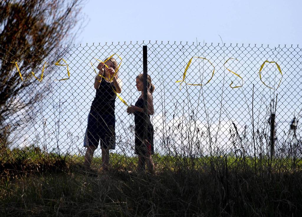 Ava Yeckley and Darby Morgan, both Arlington residents, put up a sign reading  We heart Oso on the 530 highway, Tuesday, April 1, 2014, near Arlington, Wash. (Sofia Jaramillo / The Herald)