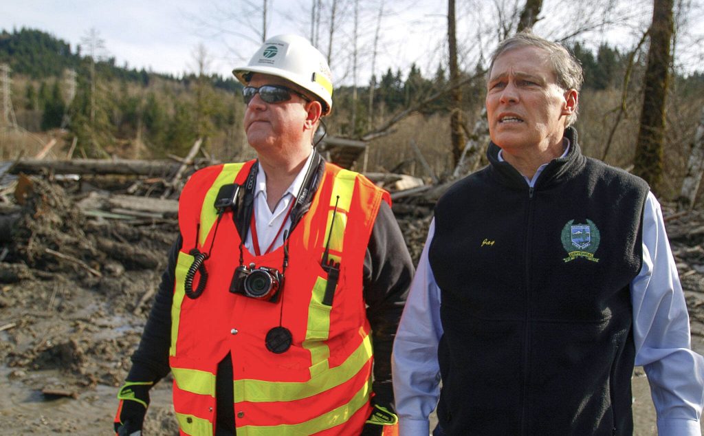 DOT Safety Manager Mike Breysse (left) and Washington Governor Jay Inslee watch search and rescue efforts at the site of a crushed house on SR 530 in Oso on Monday, March 24, 2014. (Dan Bates / The Herald)