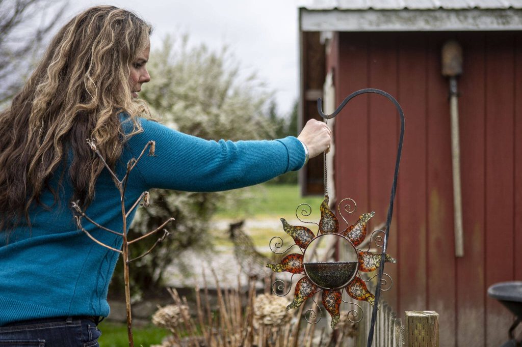 Julie Petersen adjusts a sunflower garden ornament in a section of her garden dedicated to her sister Christina Jefferds at her home on March 20, 2024 in Arlington, Washington. (Annie Barker / The Herald)