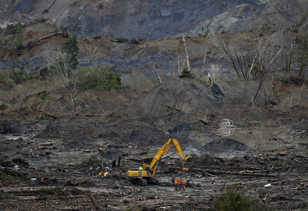 Rescue workers sift through the mud and debris at the Oso, Washington mudslide site on March 30, 2014. (Annie Mulligan / For The Herald)