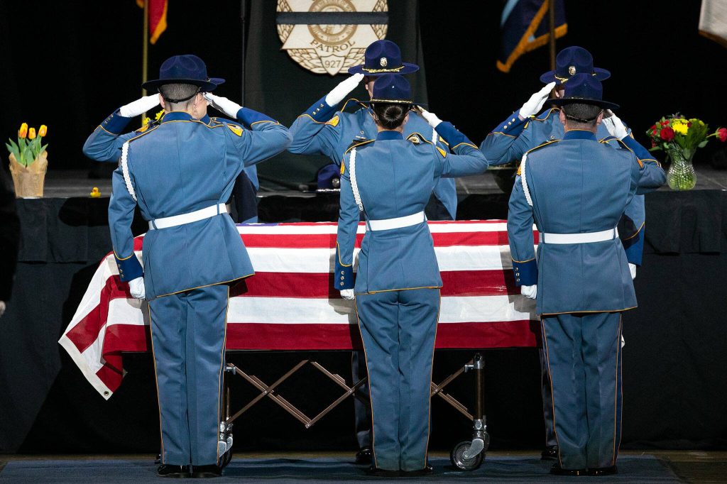 Members of the Washington State Patrol salute the casket of fallen trooper Chris Gadd during a memorial ceremony on Tuesday, March 12, 2024, at Angel of the Winds Arena in Everett, Washington. (Ryan Berry / The Herald)