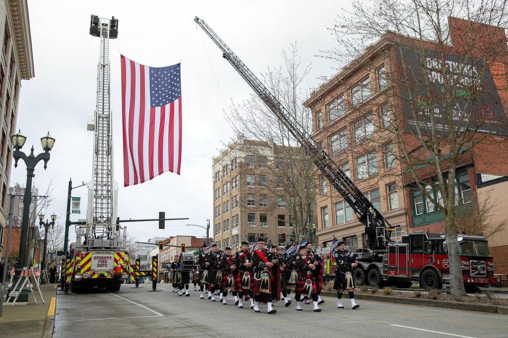 Bagpipes and drums lead a procession down Hewitt Avenue during a memorial for Washington State Patrol trooper Chris Gadd on Tuesday, March 12, 2024, outside Angel of the Winds Arena in Everett, Washington. (Ryan Berry / The Herald)