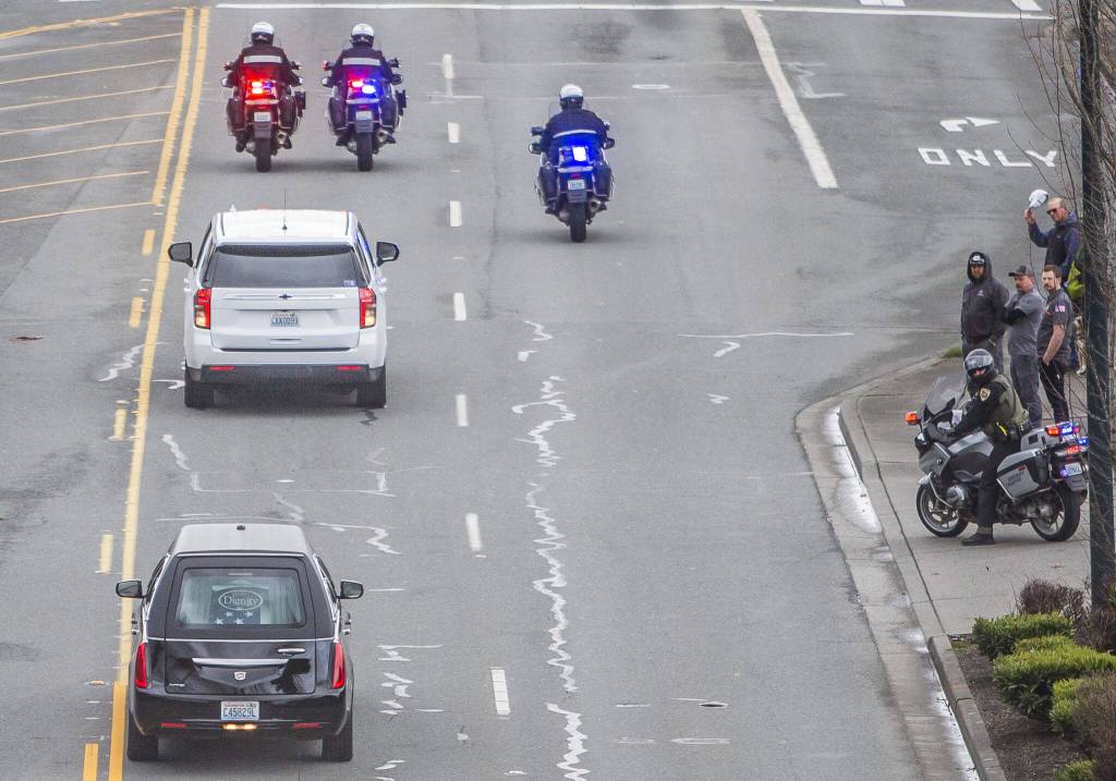 People watch as the hearse carrying Washington State Trooper Christopher Gadd passes by along Marine View Drive on Tuesday, March 12, 2024 in Everett, Washington. (Olivia Vanni / The Herald)