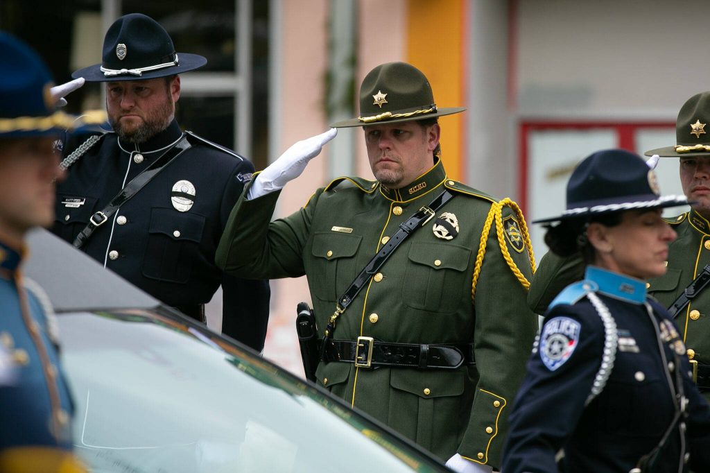 Law enforcement officers salute Washington State Patrol trooper Chris Gadds casket during a procession on Tuesday, March 12, 2024, at Angel of the Winds Arena in Everett, Washington. (Ryan Berry / The Herald)