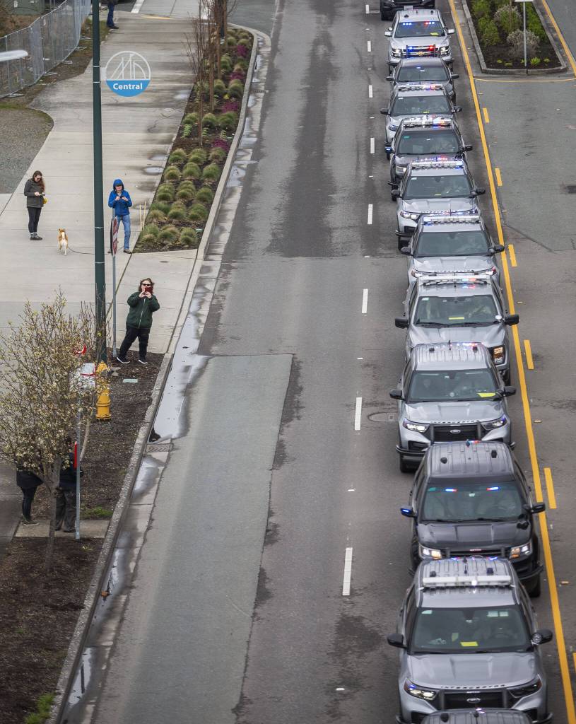 Police cars stop along Marine View Drive during a memorial procession for Washington State Patrol trooper Christopher Gadd on Tuesday, March 12, 2024 in Everett, Washington. (Olivia Vanni / The Herald)
